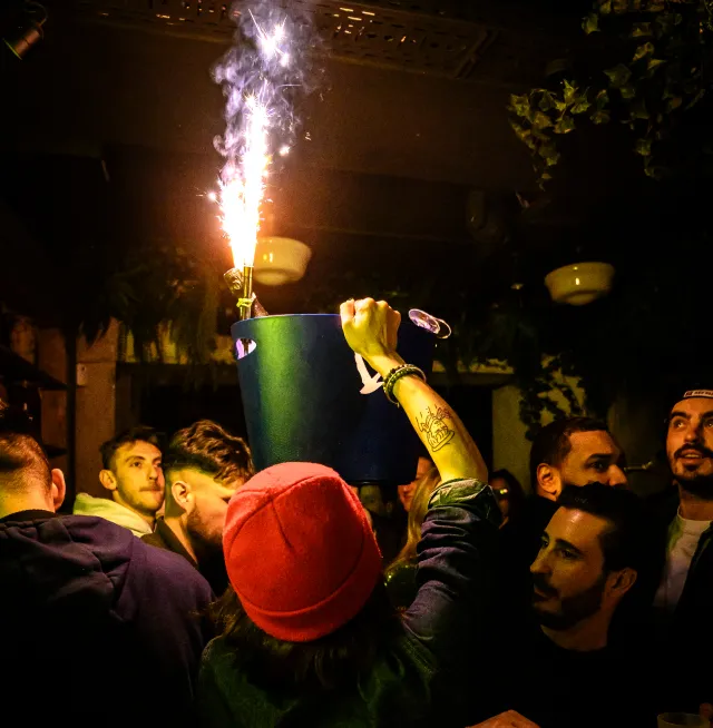 Serveur qui porte un sceau contenant une bouteille de champagne avec bougie magique